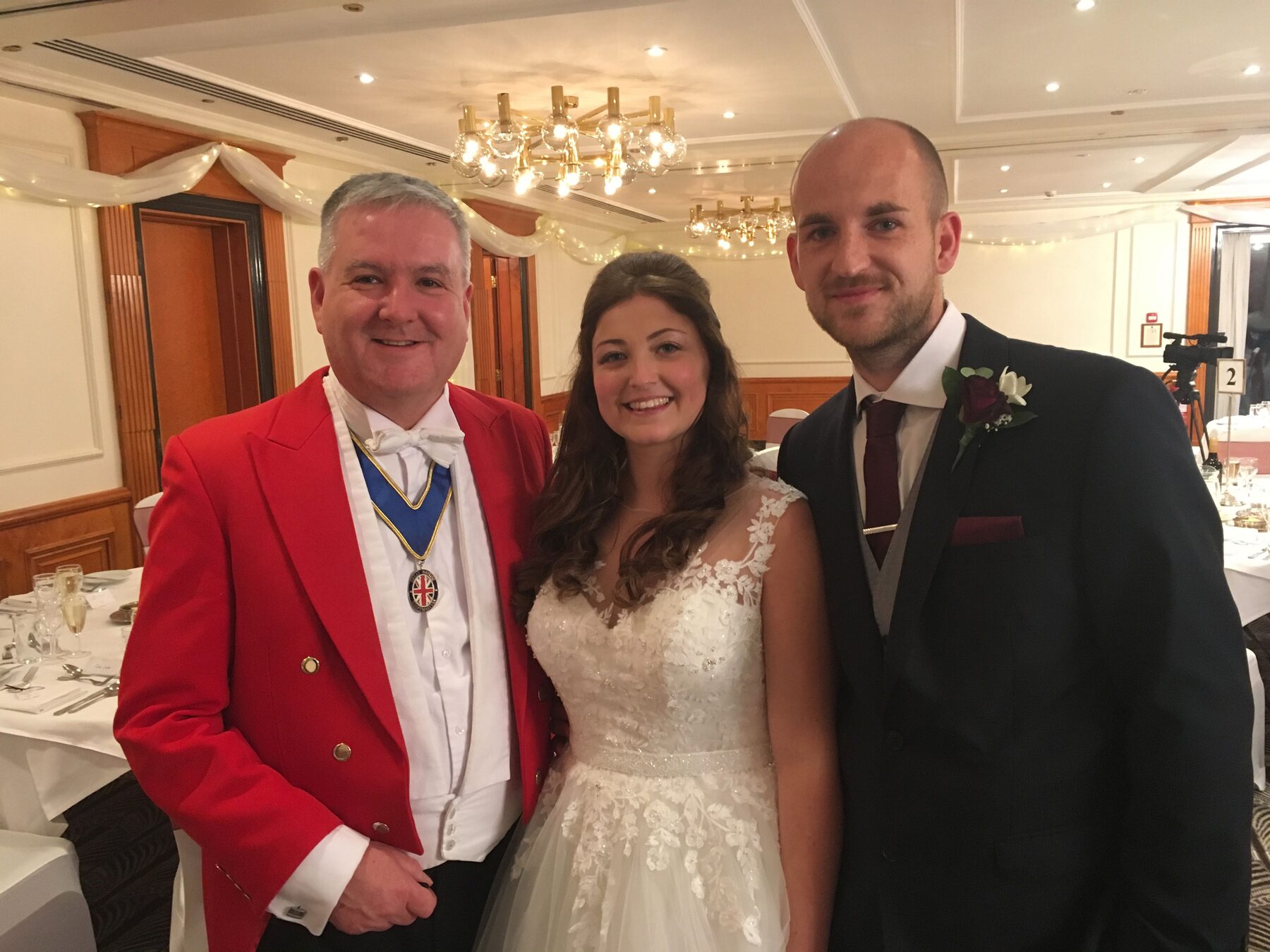 Andrew Morgan at a wedding, with the bride and groom in the background